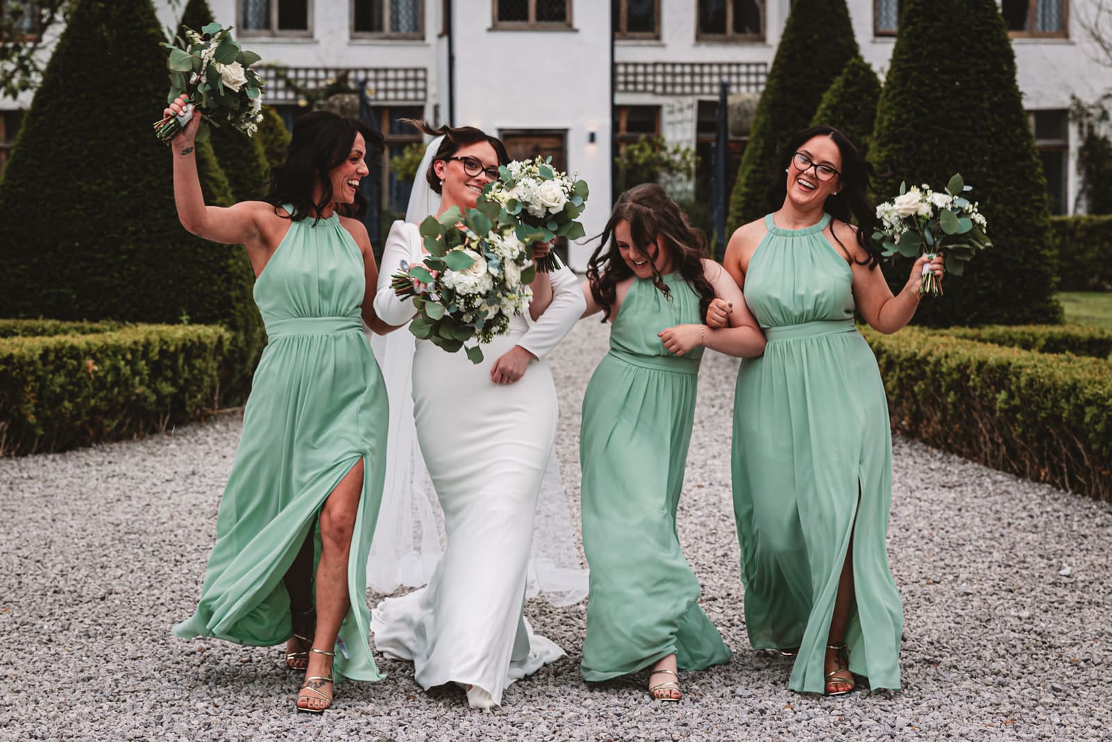 bridesmaids in pale green bridesmaid dresses walking with bride in middle at riverbarn poulton