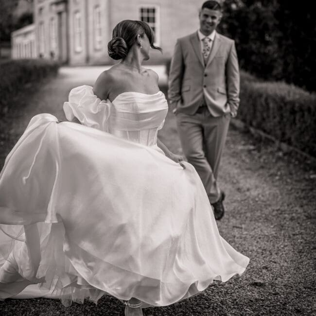 A bride walking away from her groom in black and white with the dress flowing high at grassfield harrogate | Yorksire wedding photographer