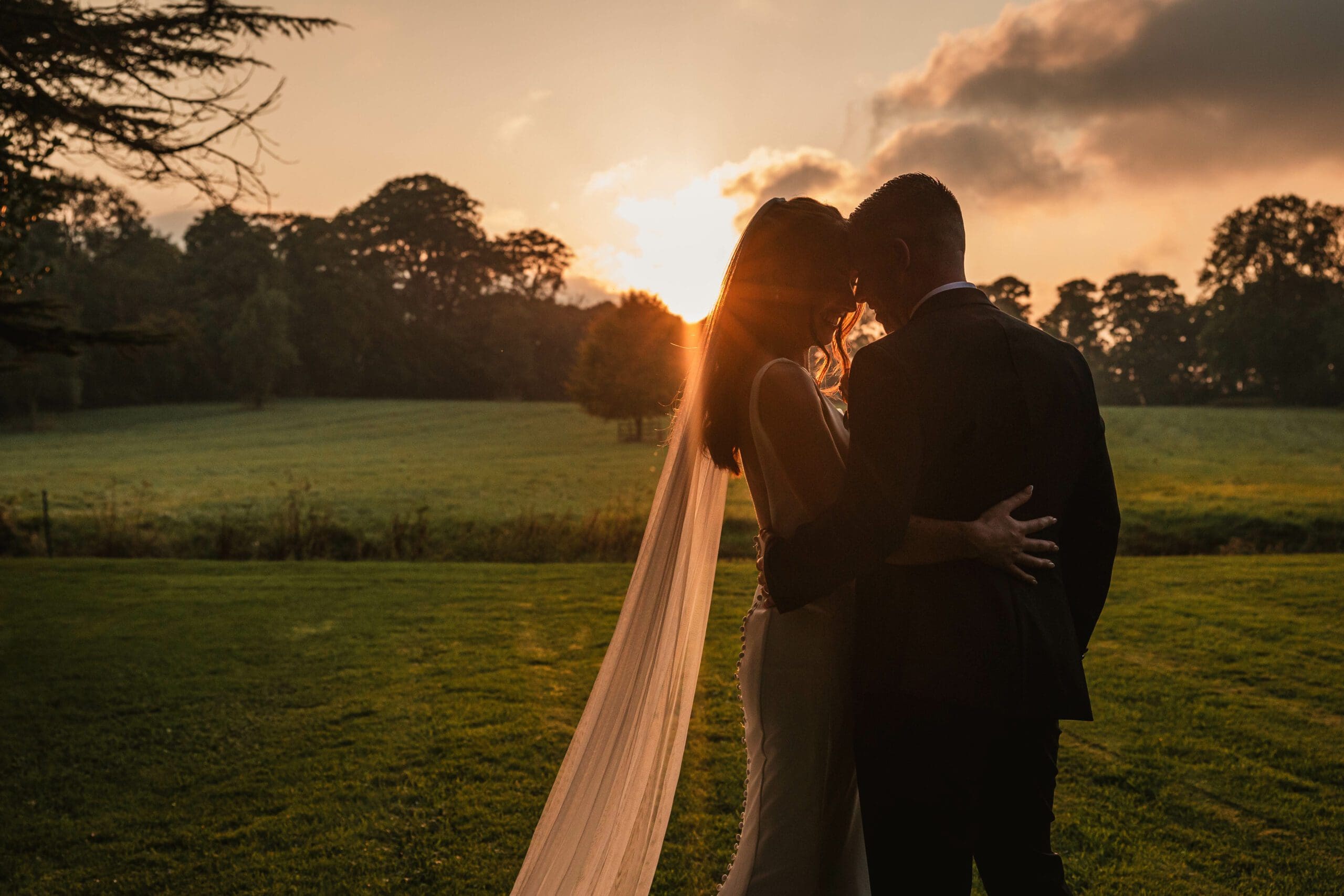 A golden hour sunset photo of a bride and groom taken at tissington hall | by a west Yorkshire wedding photographer