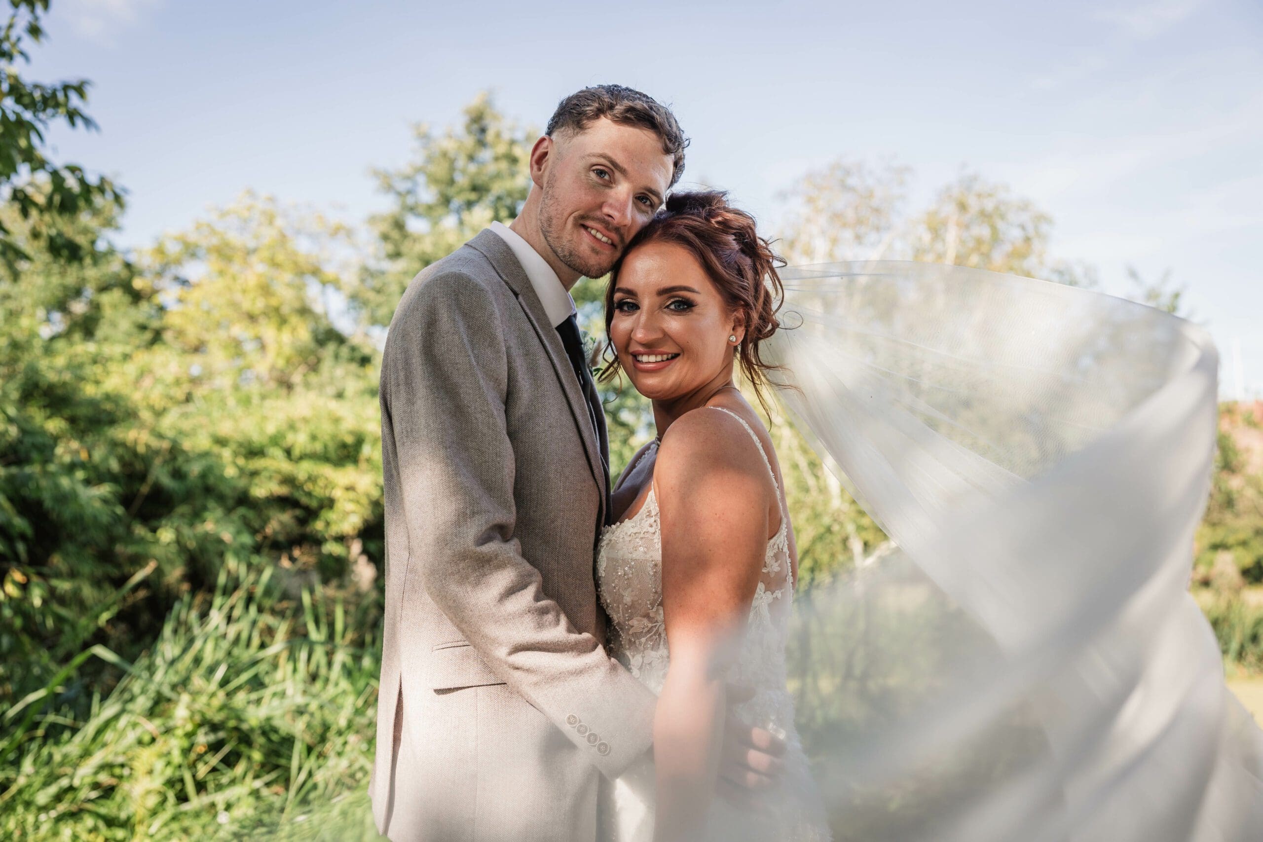 Bride and groom at hodsock priory with the wind sweeping the vail