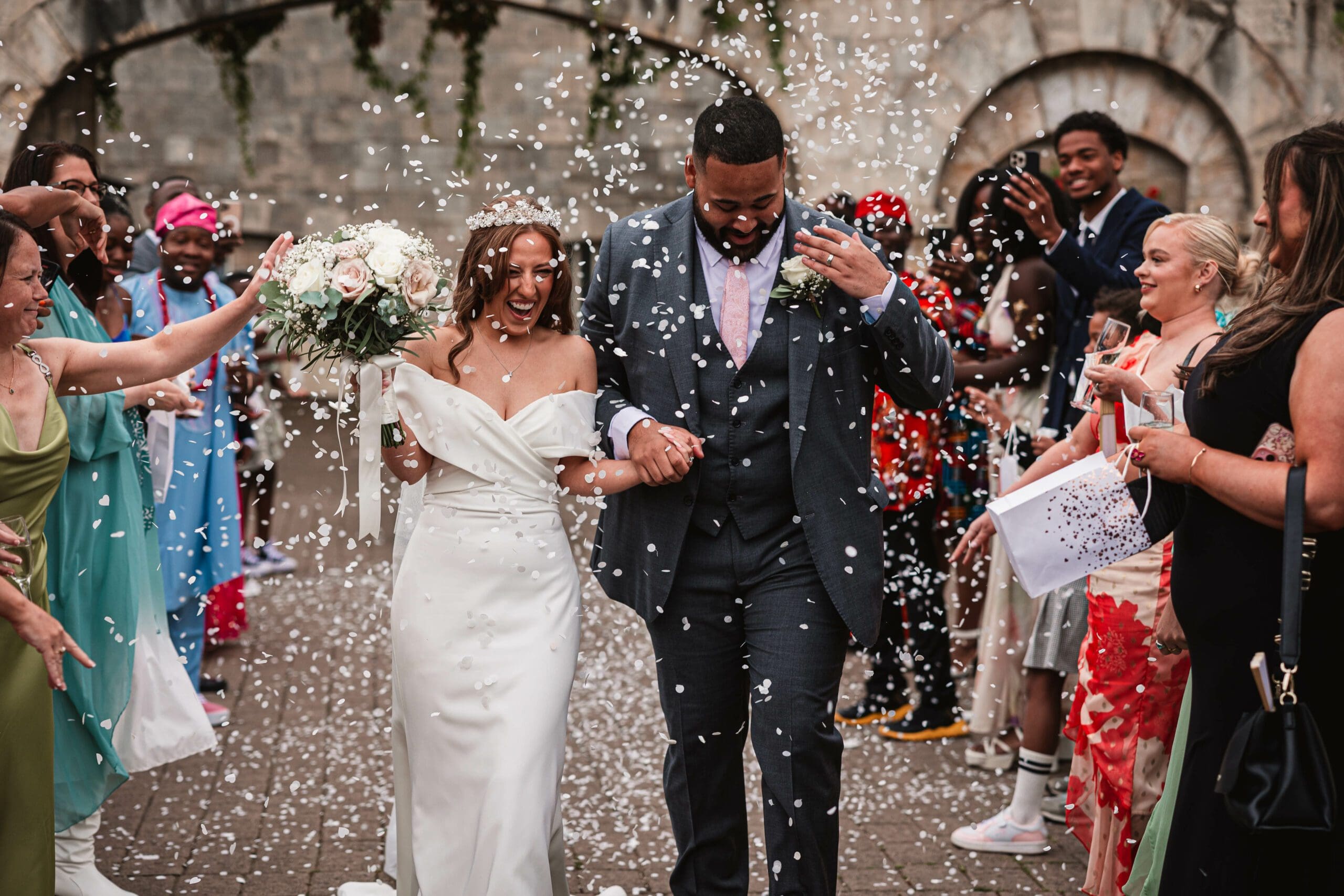 White conffeti being thrown at hazzlewood castle as the bride and groom walk through | as a west Yorkshire wedidng